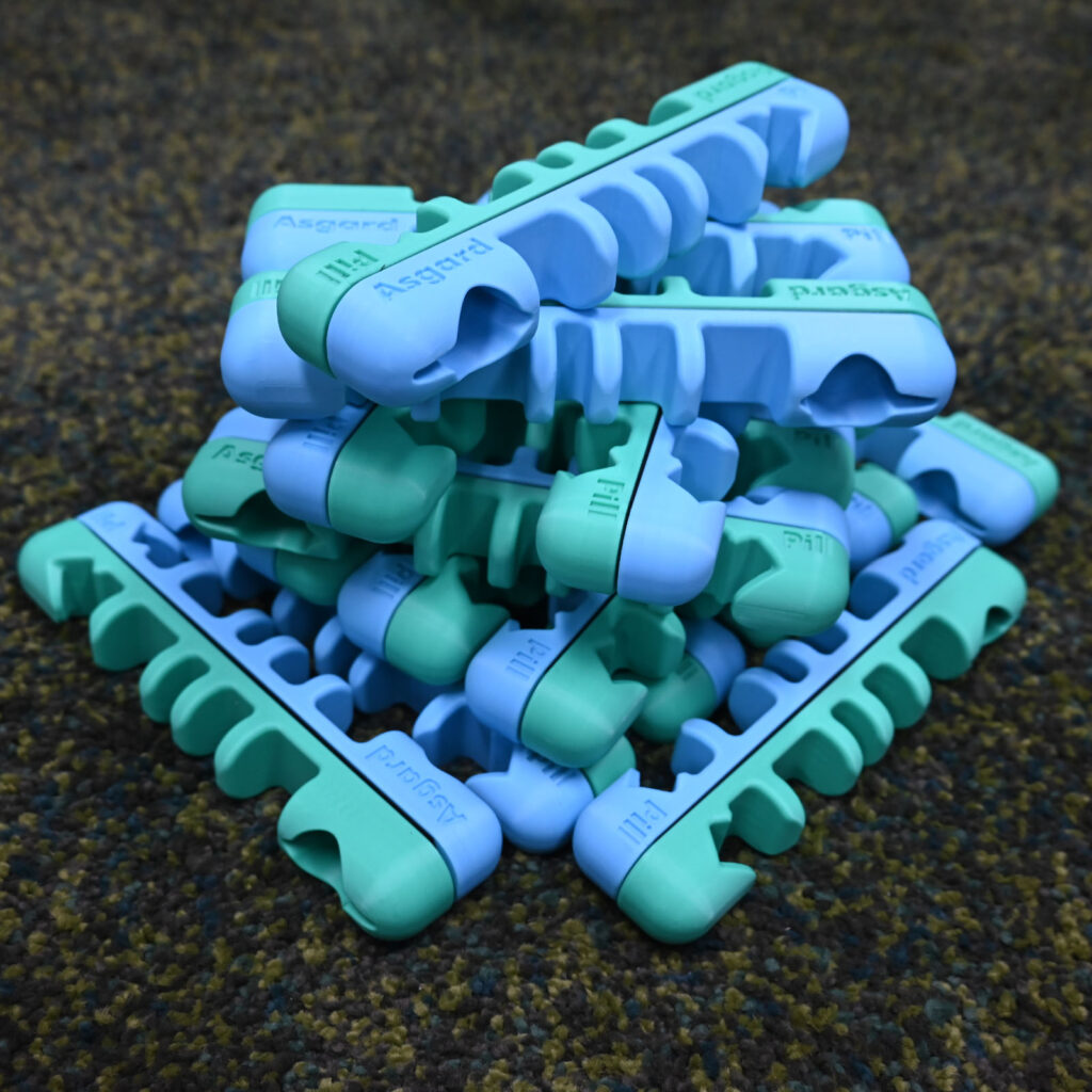 Pile of blue and green Asgard Pill magnetic ski and snowboard holders on dark textured background