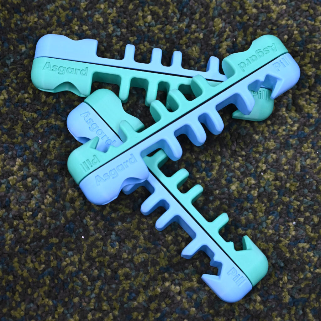 Blue and green Asgard Pill magnetic holders arranged together on a textured surface