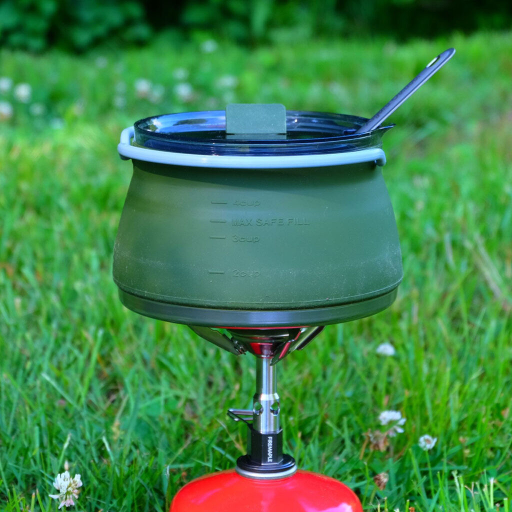 Olive Asgard collapsible camping pot on red stove outdoors