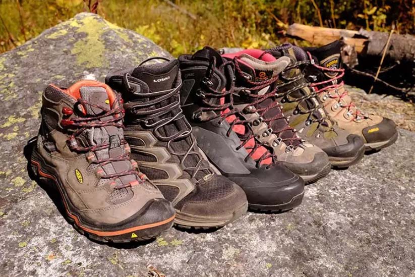 Four pairs of hiking boots on a rock in a natural setting