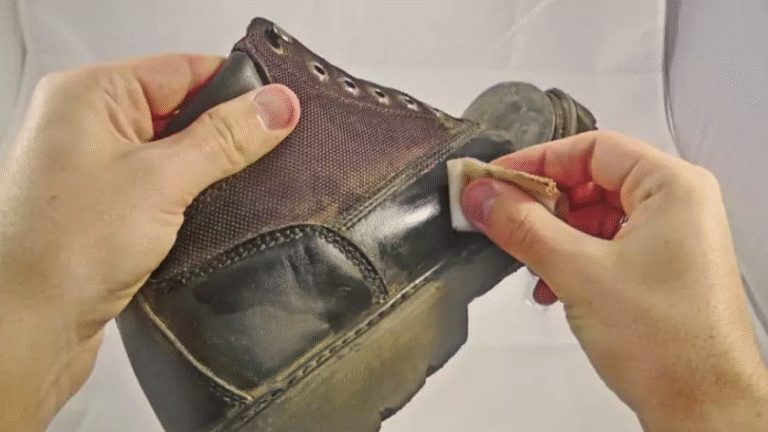 A person polishing a black leather boot with a cloth