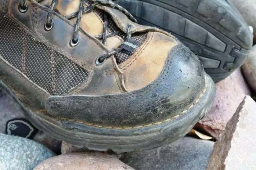 Muddy hiking boots on a pile of rocks outdoors