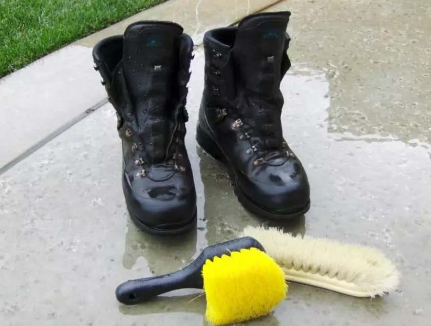 Wet hiking boots with cleaning brushes on a wet surface