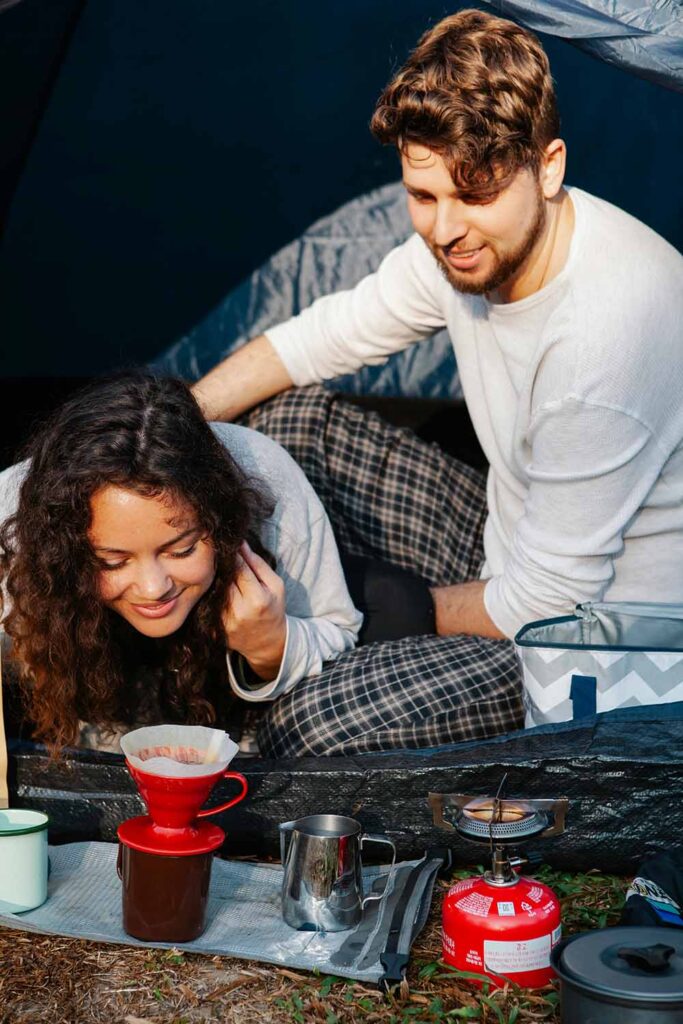 Couple making pour-over coffee at their campsite