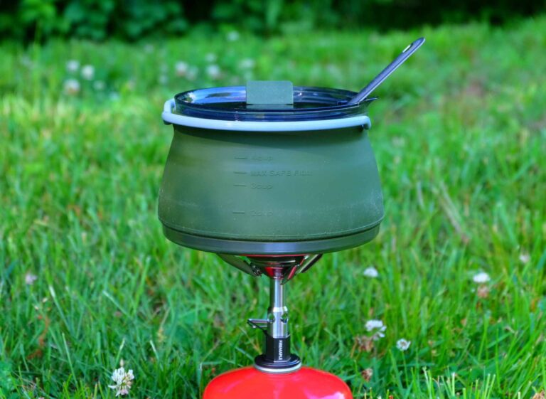 Foldable camping coffee pot heating on grass with gas stove