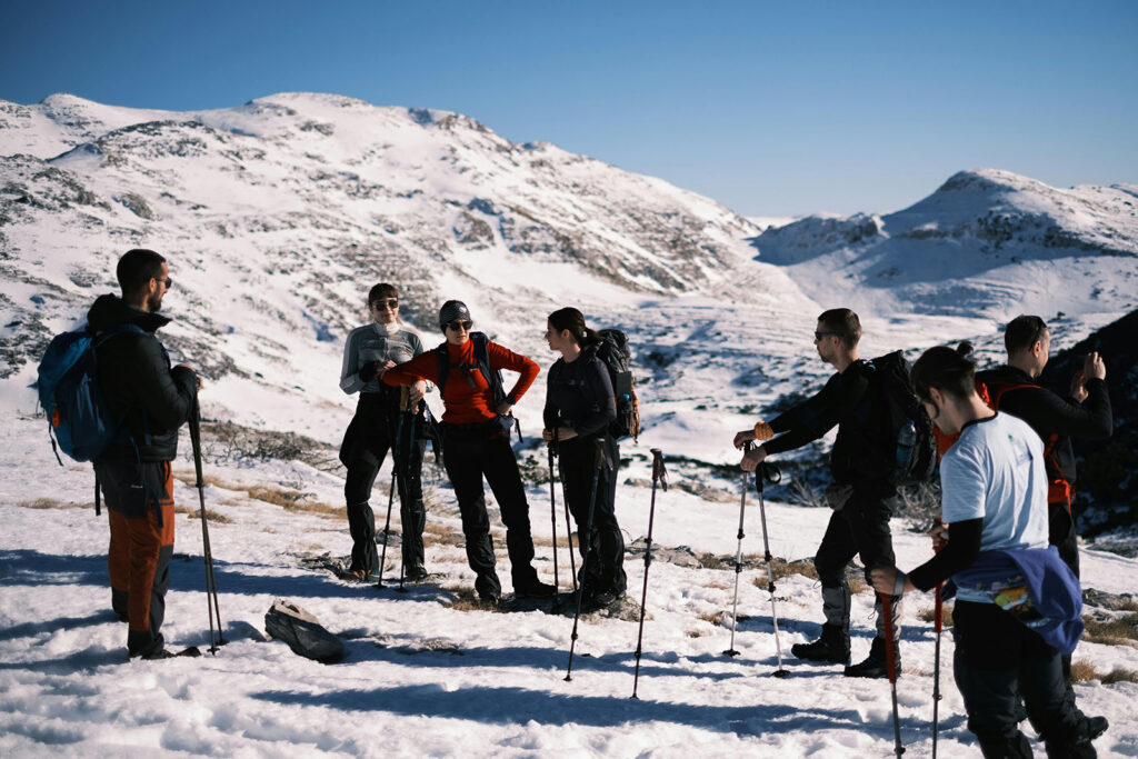 Group of hikers with hiking poles in snowy mountains
