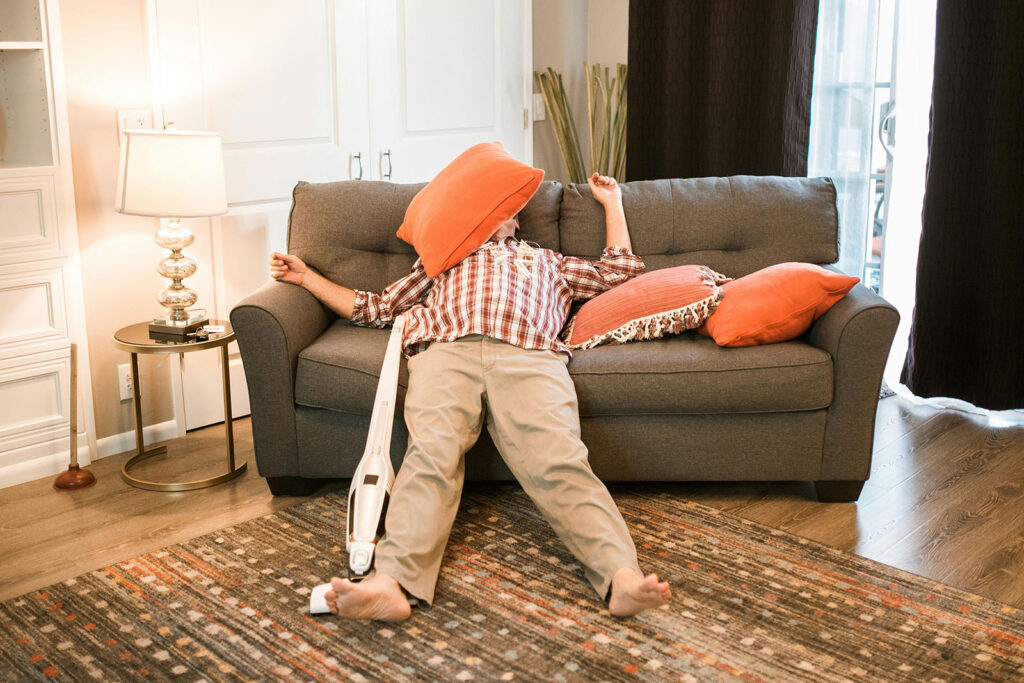 A man relaxing on a couch with a pillow on his face
