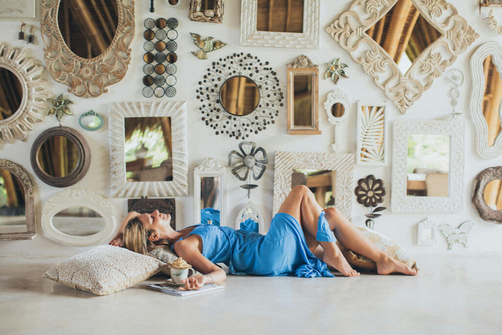 Woman in blue dress reclining on pillows against wall of mirrors