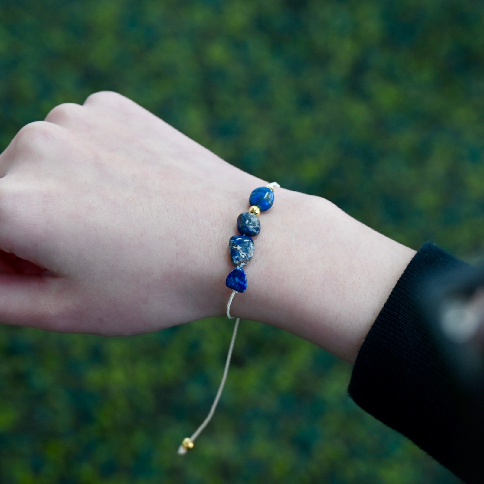 Close-up of Asgard Abyss ID lapis mineral bracelet on wrist showing mixed blue mineral beads and adjustable cord.