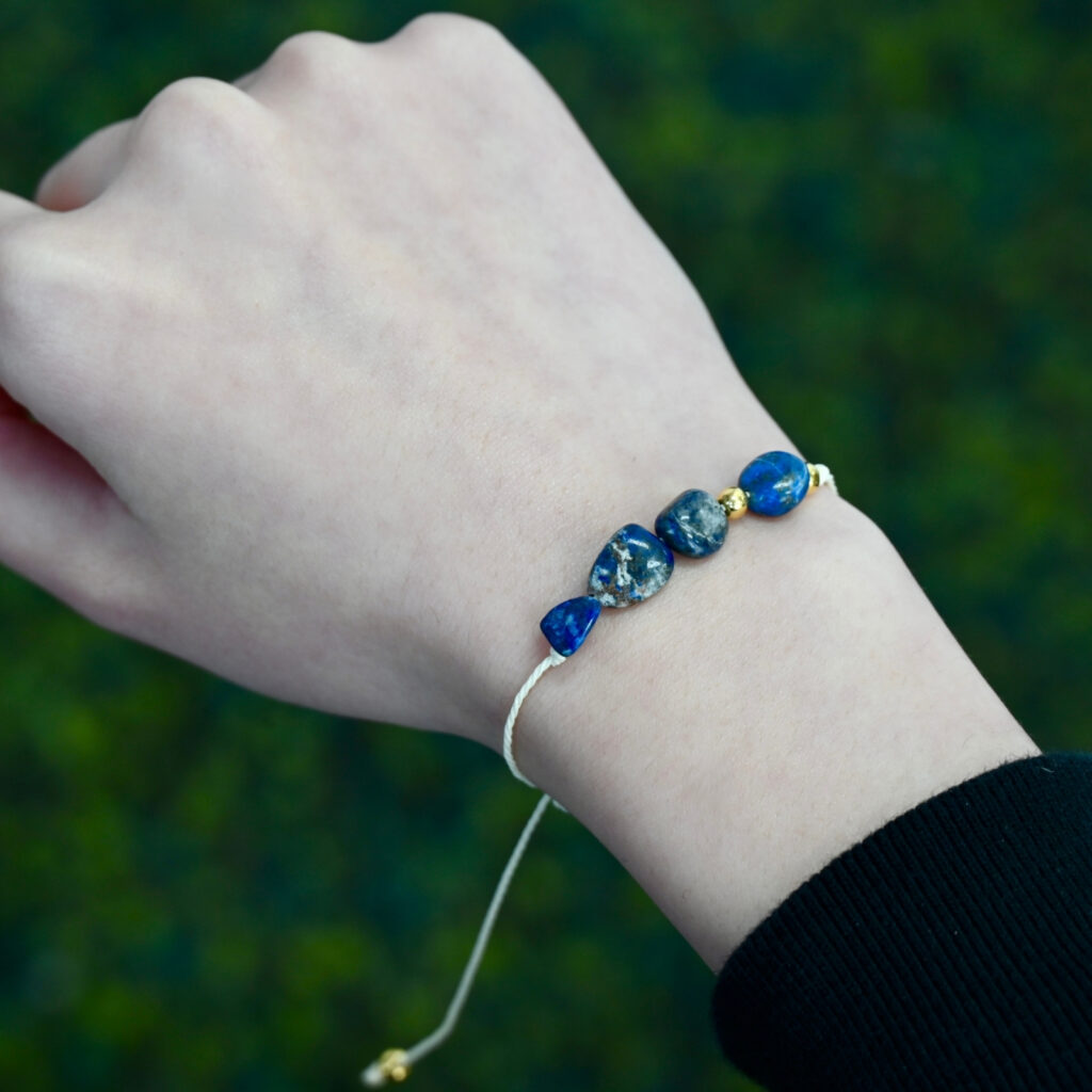 Asgard Abyss ID lapis mineral bracelet worn on wrist with deep blue stone beads and cream adjustable cord.