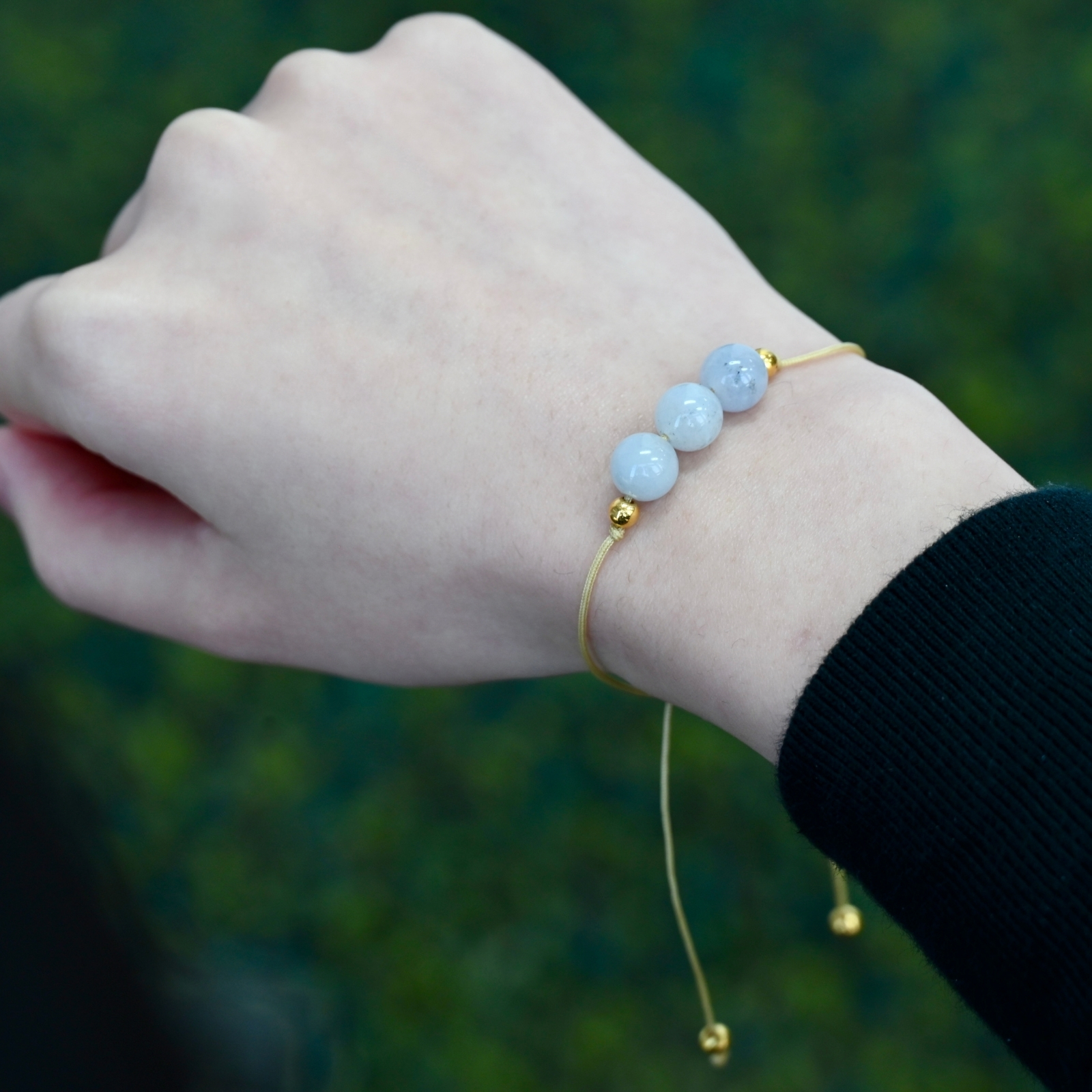 Close-up of Asgard Glacier ID mist mineral bracelet on wrist with pale blue beads and gold-tone accents.