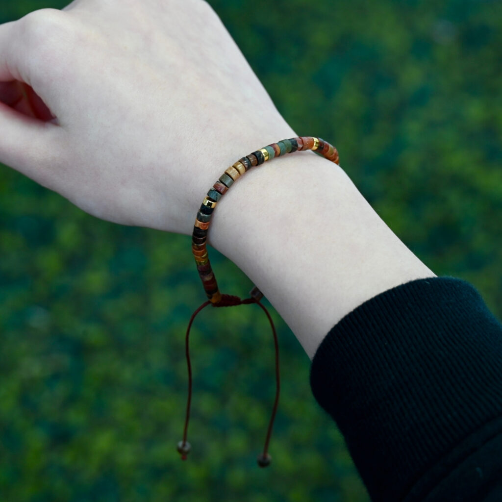Close view of Asgard Terra ID adjustable earth-tone mineral bracelet on wrist with slim disc beads and hanging brown cord.