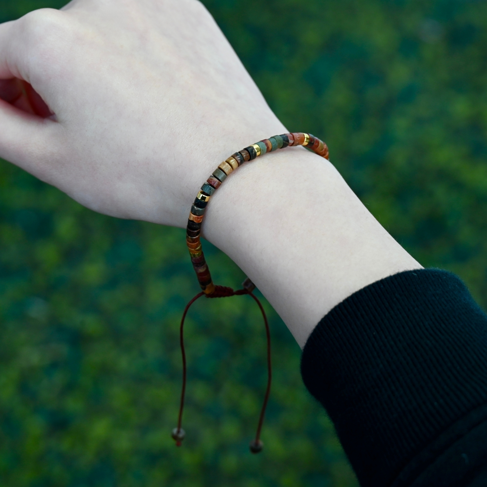 Close view of Asgard Terra ID adjustable earth-tone mineral bracelet on wrist with slim disc beads and hanging brown cord.