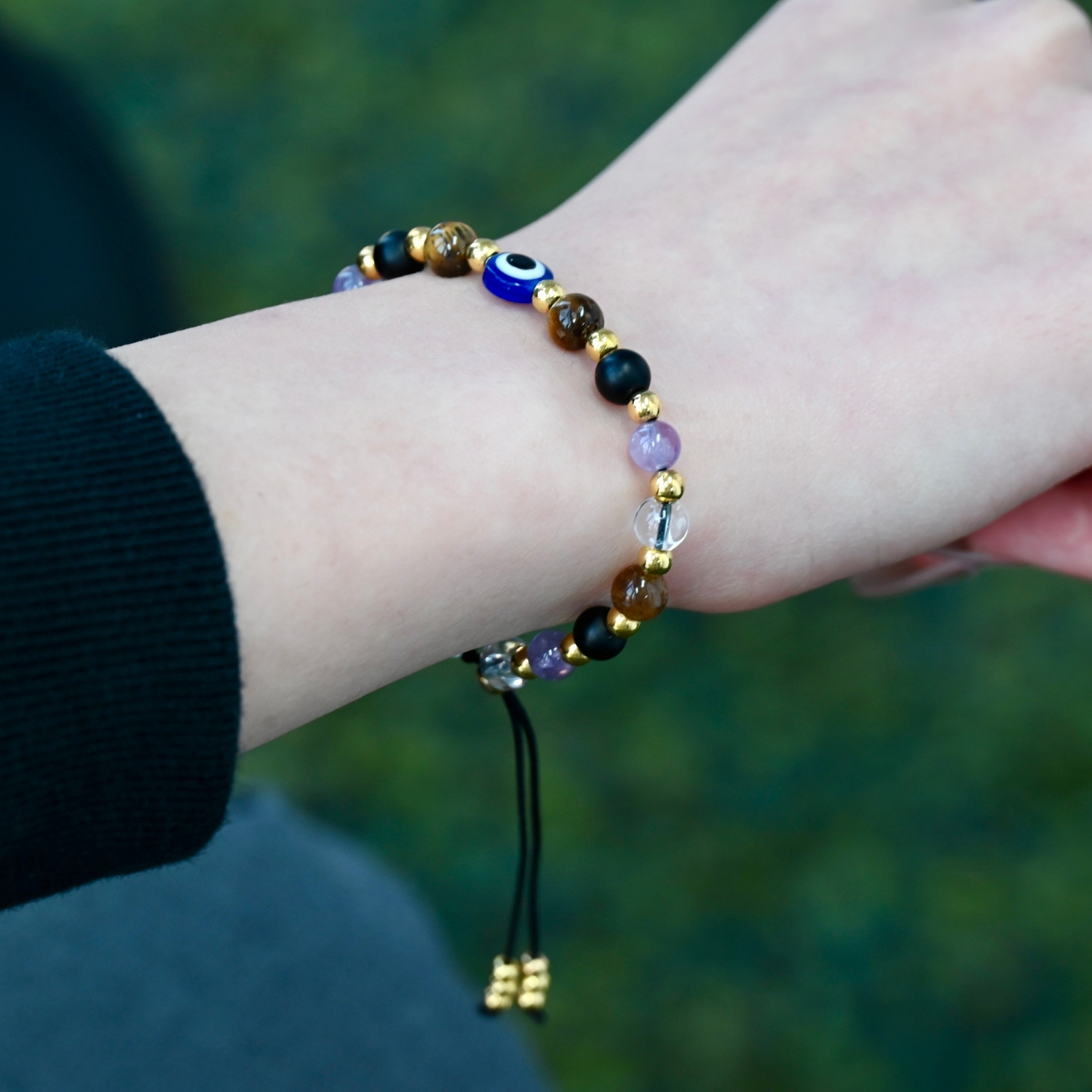 Person wearing the Asgard Vigil ID natural stone bracelet with gold-tone accents and a blue eye-style center bead.