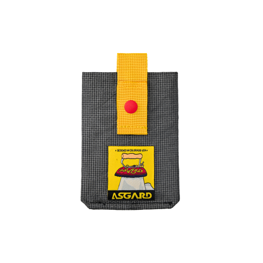 Dark gray Asgard MagSafe card holder with a yellow pull strap, red snap and yellow logo patch.