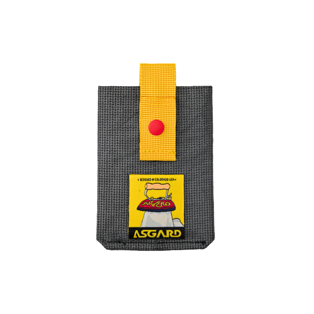 Dark gray Asgard MagSafe card holder with a yellow pull strap, red snap and yellow logo patch.