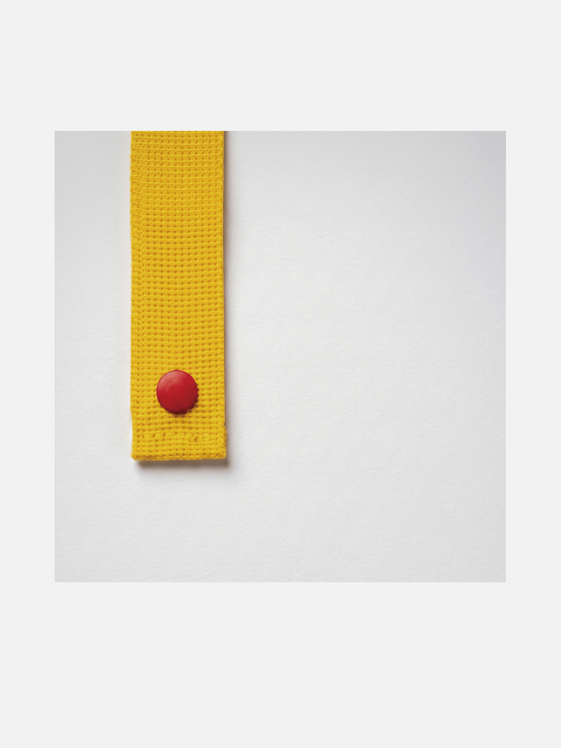 Close-up of the yellow card holder strap with a red Sungrip snap against a light background.