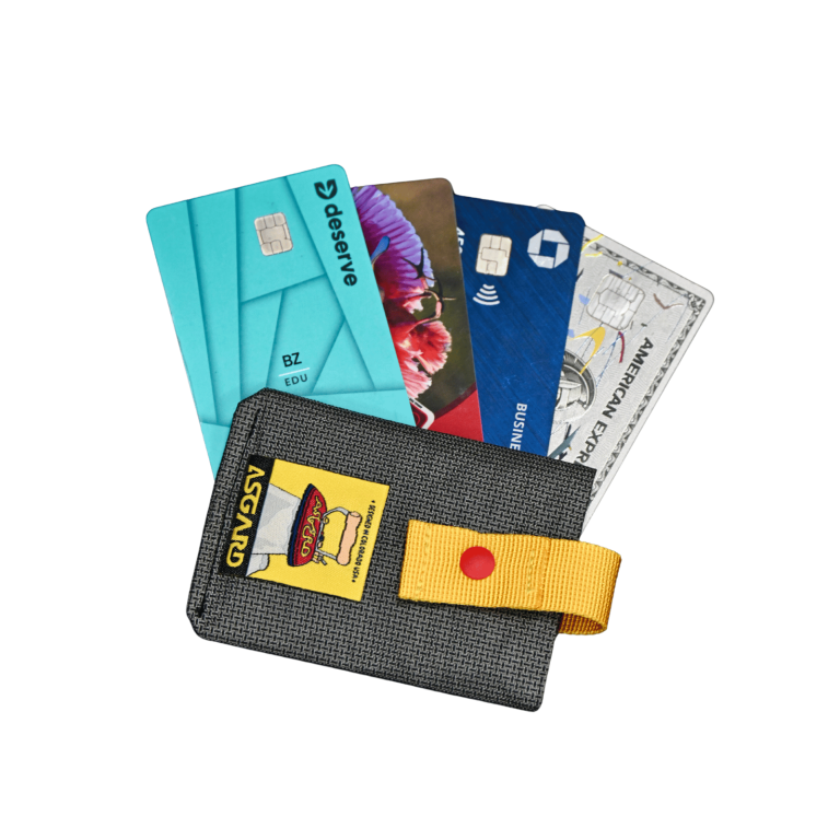 Several cards fanned out of the dark gray Asgard card holder, with its yellow strap opened to the side.