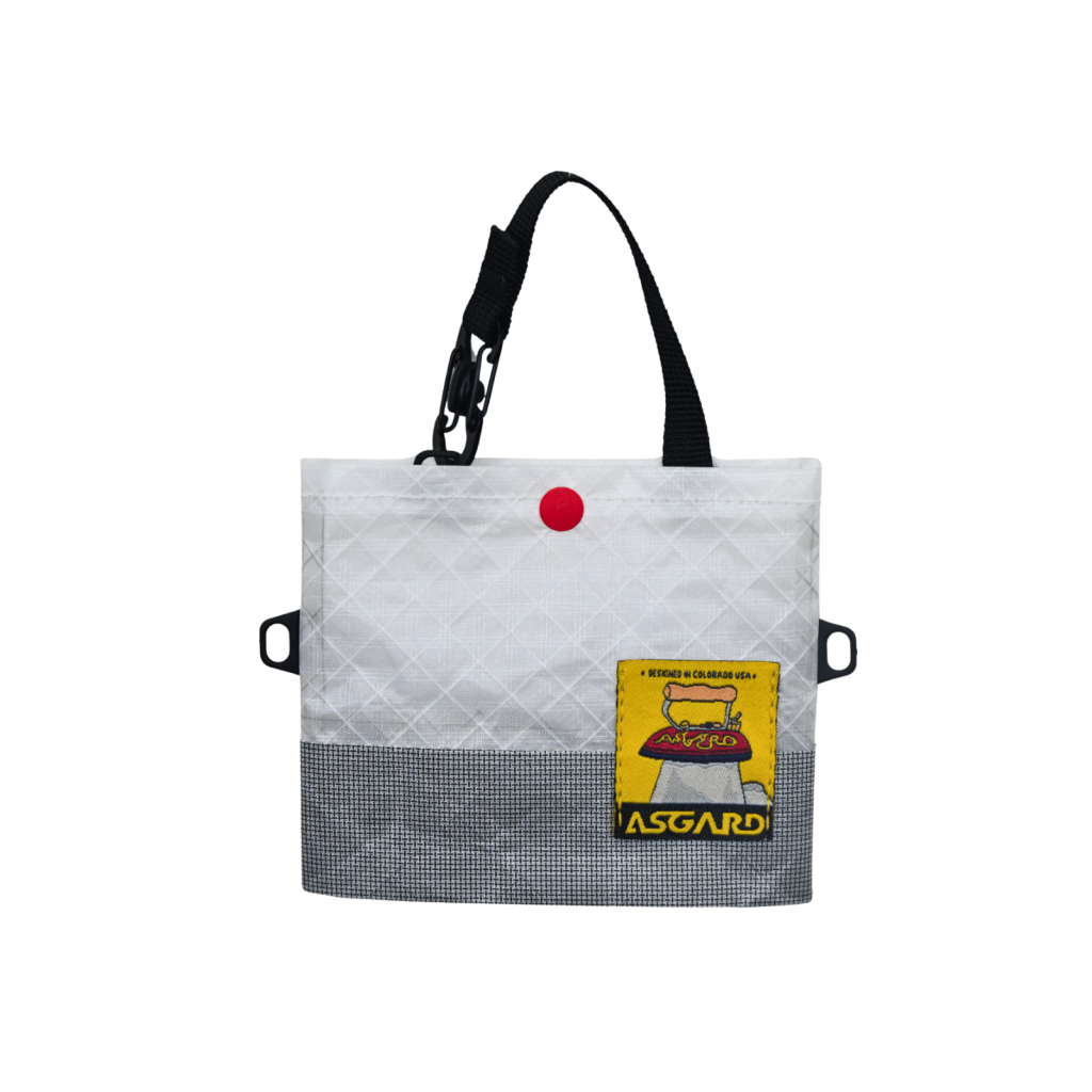 Light gray Asgard mini tote bag with black handles, a red snap and a yellow logo patch.