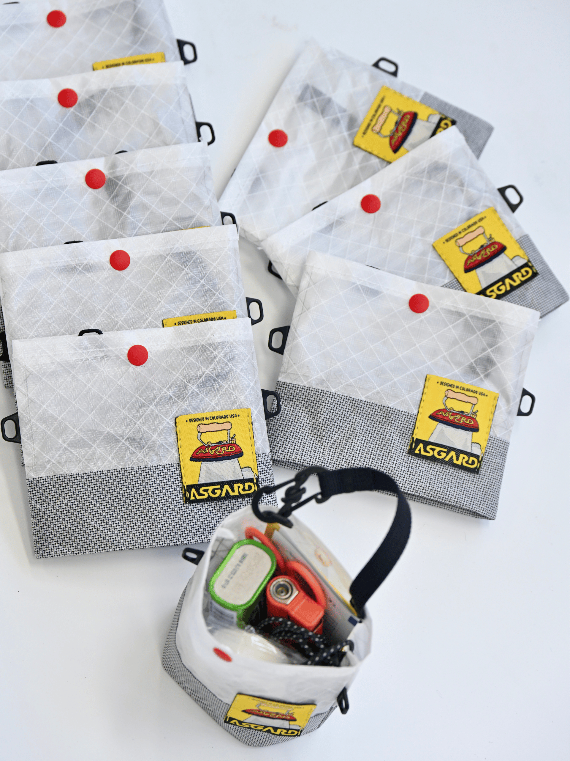 Several light gray Asgard mini totes arranged around an open bag holding small everyday items.