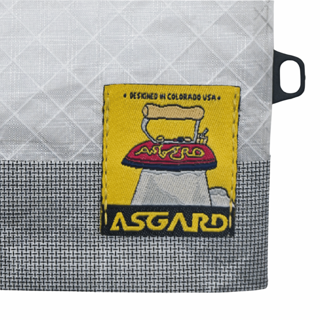 Close-up of the mini tote’s yellow Asgard patch across light gray upper fabric and dark woven lower fabric.