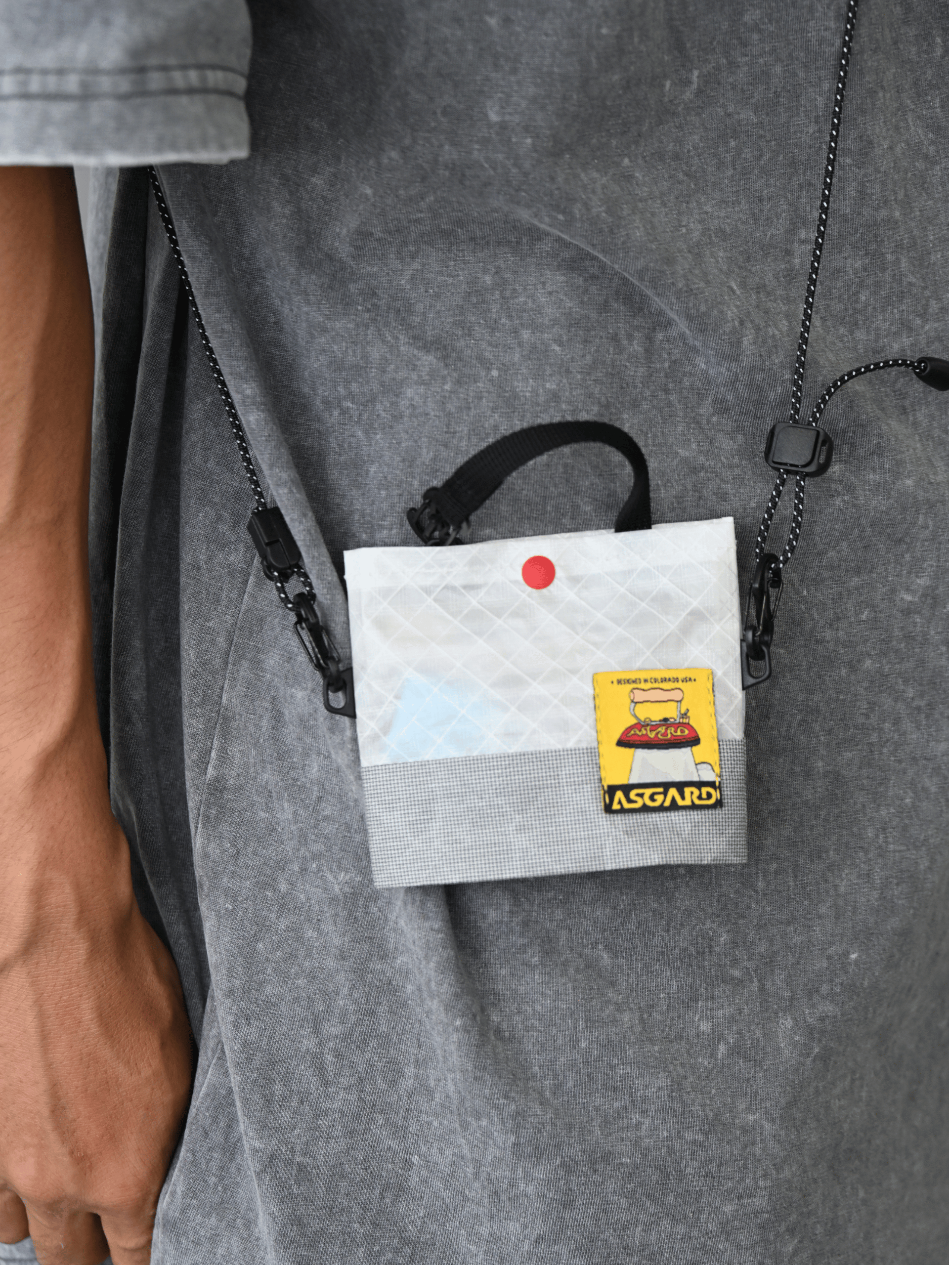 Asgard mini tote bag hanging against a gray shirt from a black cord.