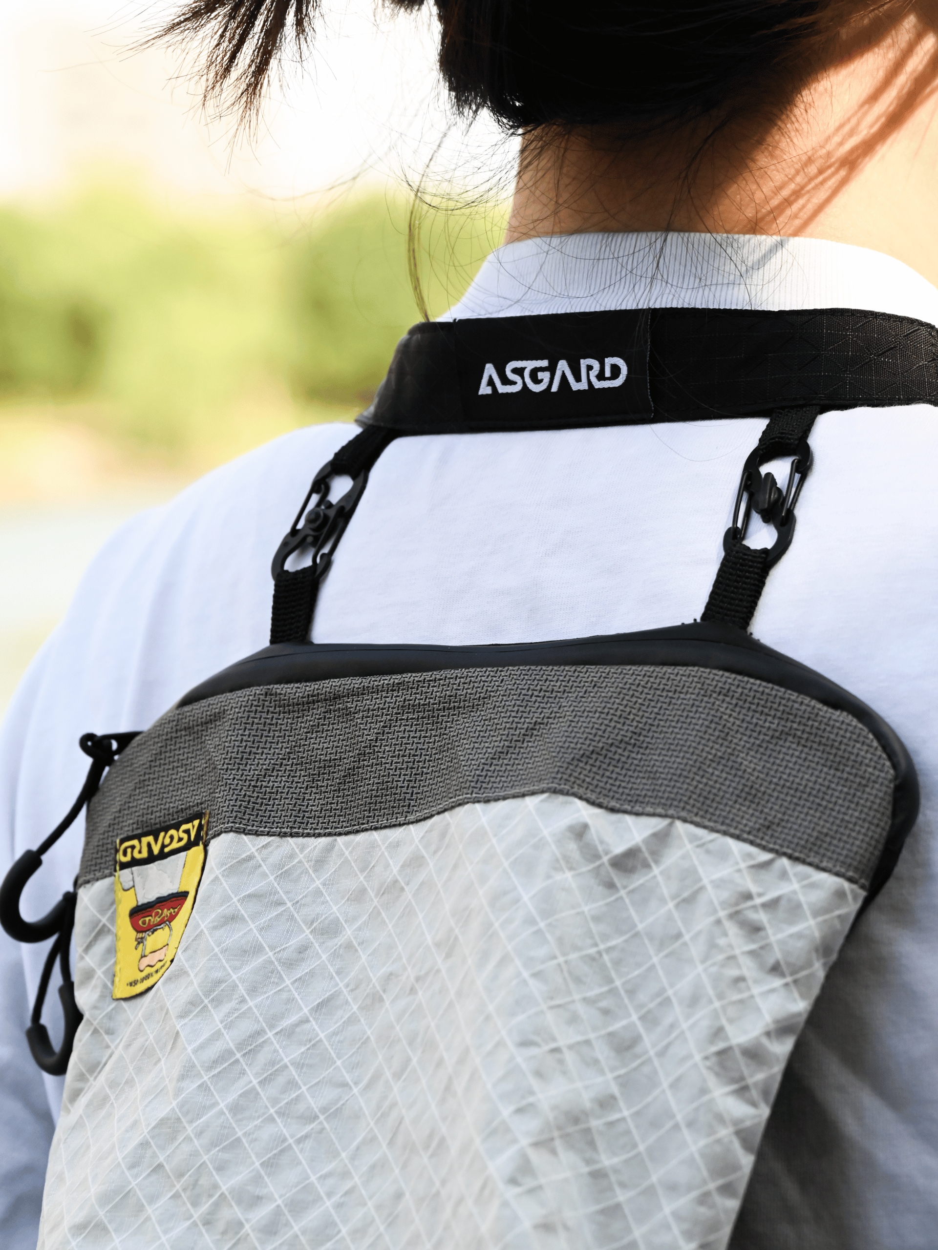 Close-up of the Asgard Versa Bag’s black shoulder strap and two figure-eight clips across a wearer’s upper back.