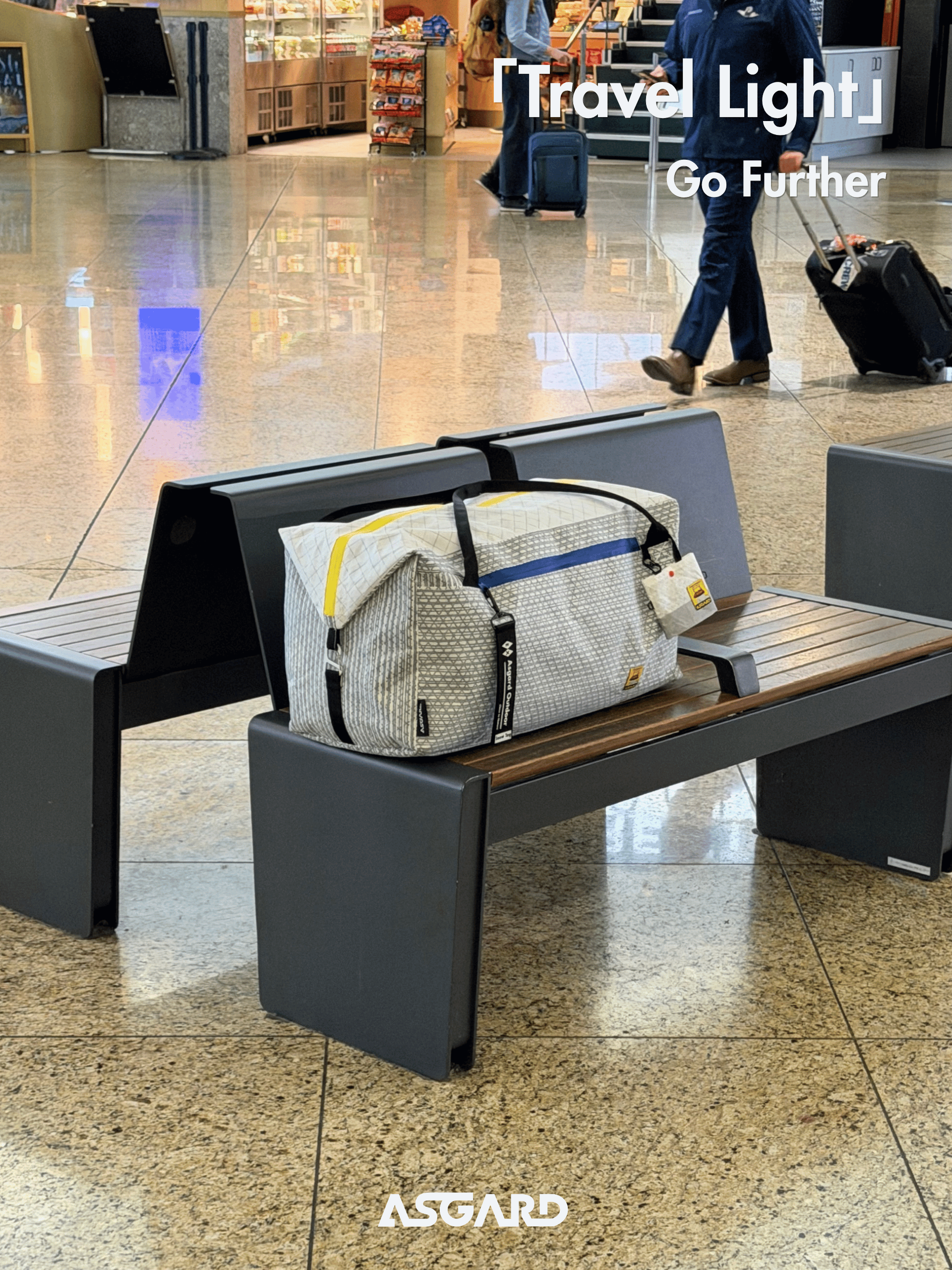 Asgard Duffel Bag resting on a bench in an airport terminal, with a traveler and rolling suitcase in the background.