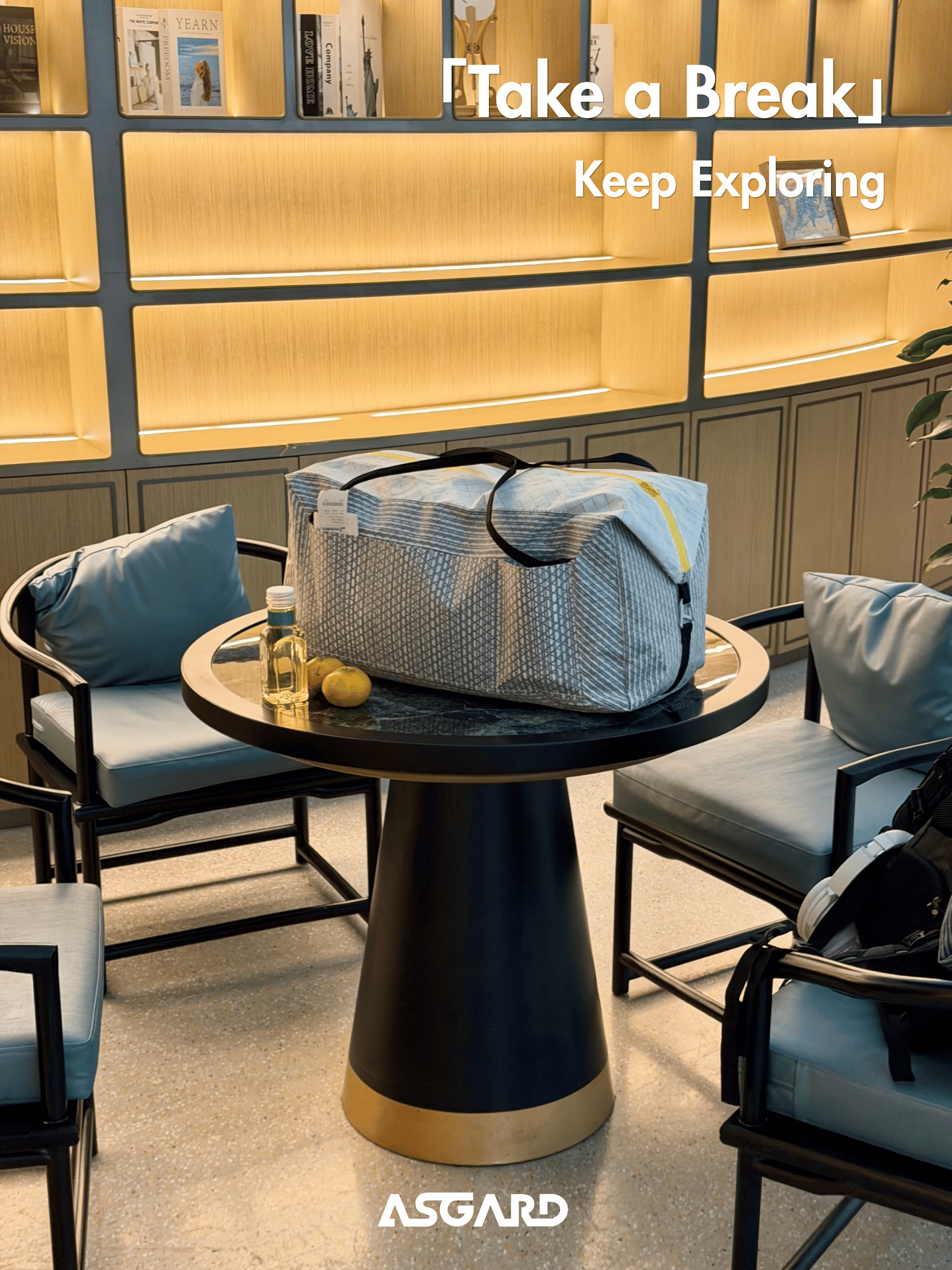 Asgard Duffel Bag on a round cafe table between lounge chairs, with a drink beside it.
