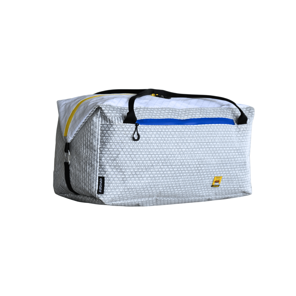 Front-left view of the Asgard Duffel Bag showing the blue front-pocket zipper, yellow top zipper and side closure.