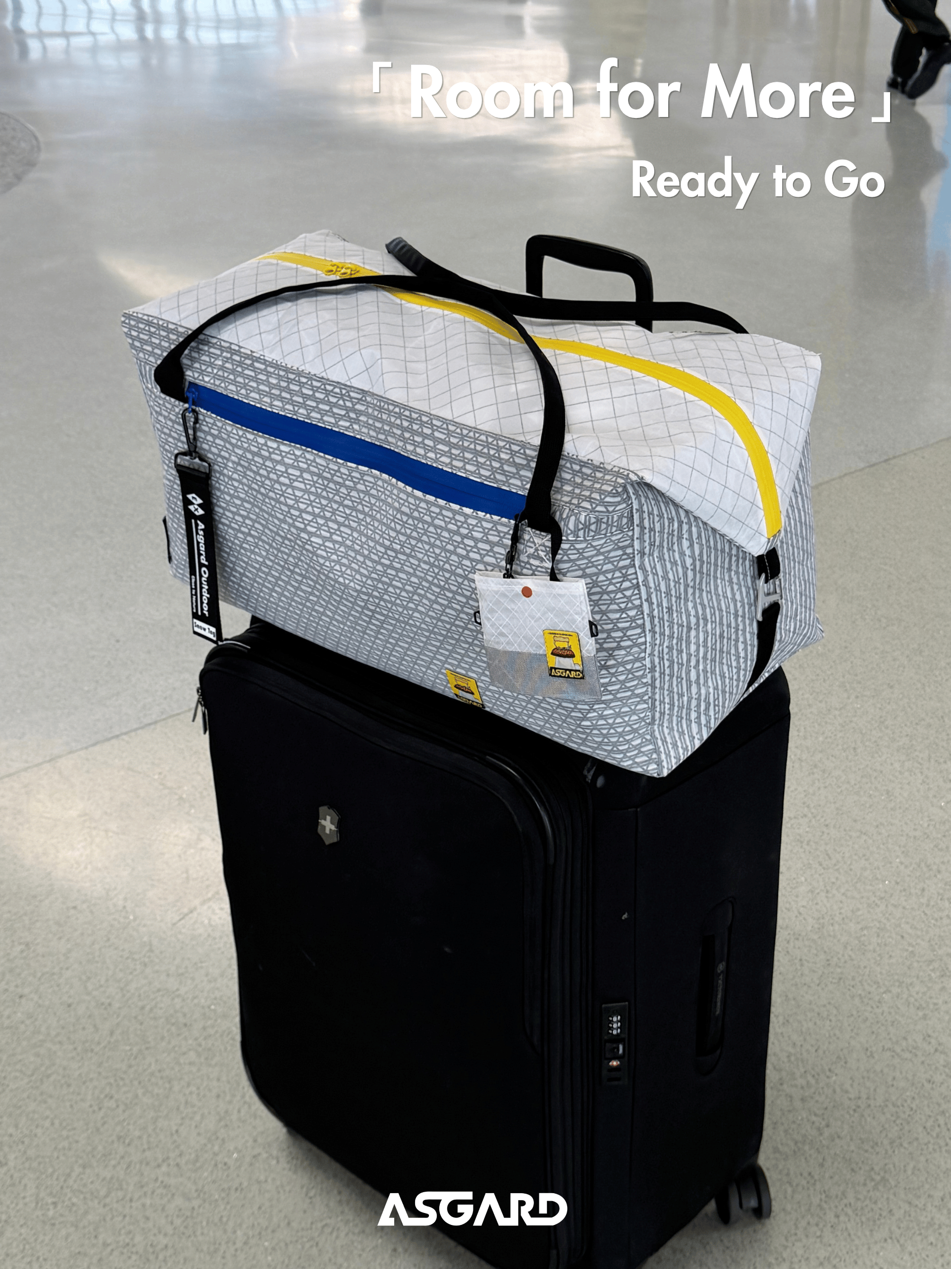 Asgard Duffel Bag resting on top of a black rolling suitcase in an airport terminal.