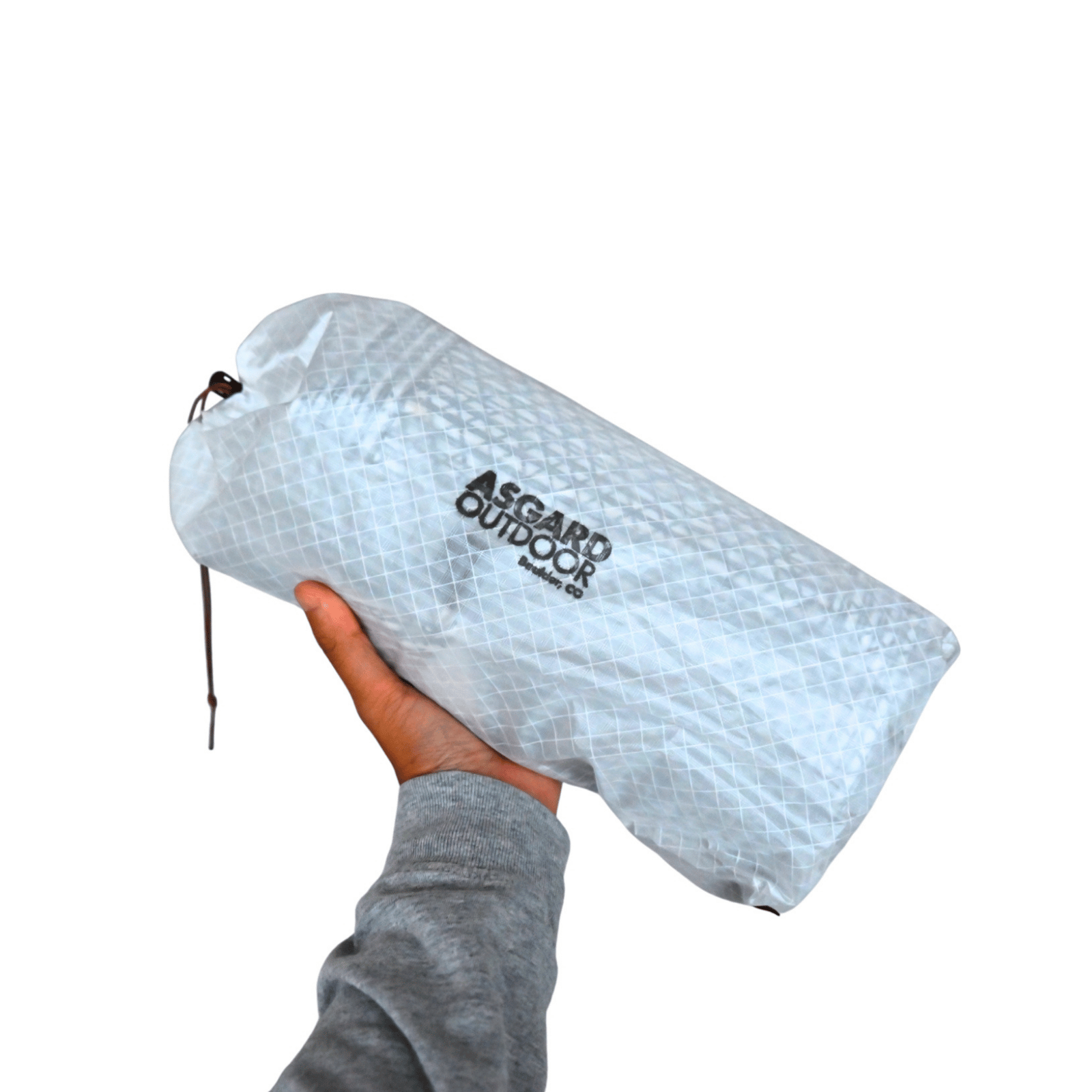 Hand holding the Asgard Duffel Bag packed inside its light gray drawstring storage pouch.
