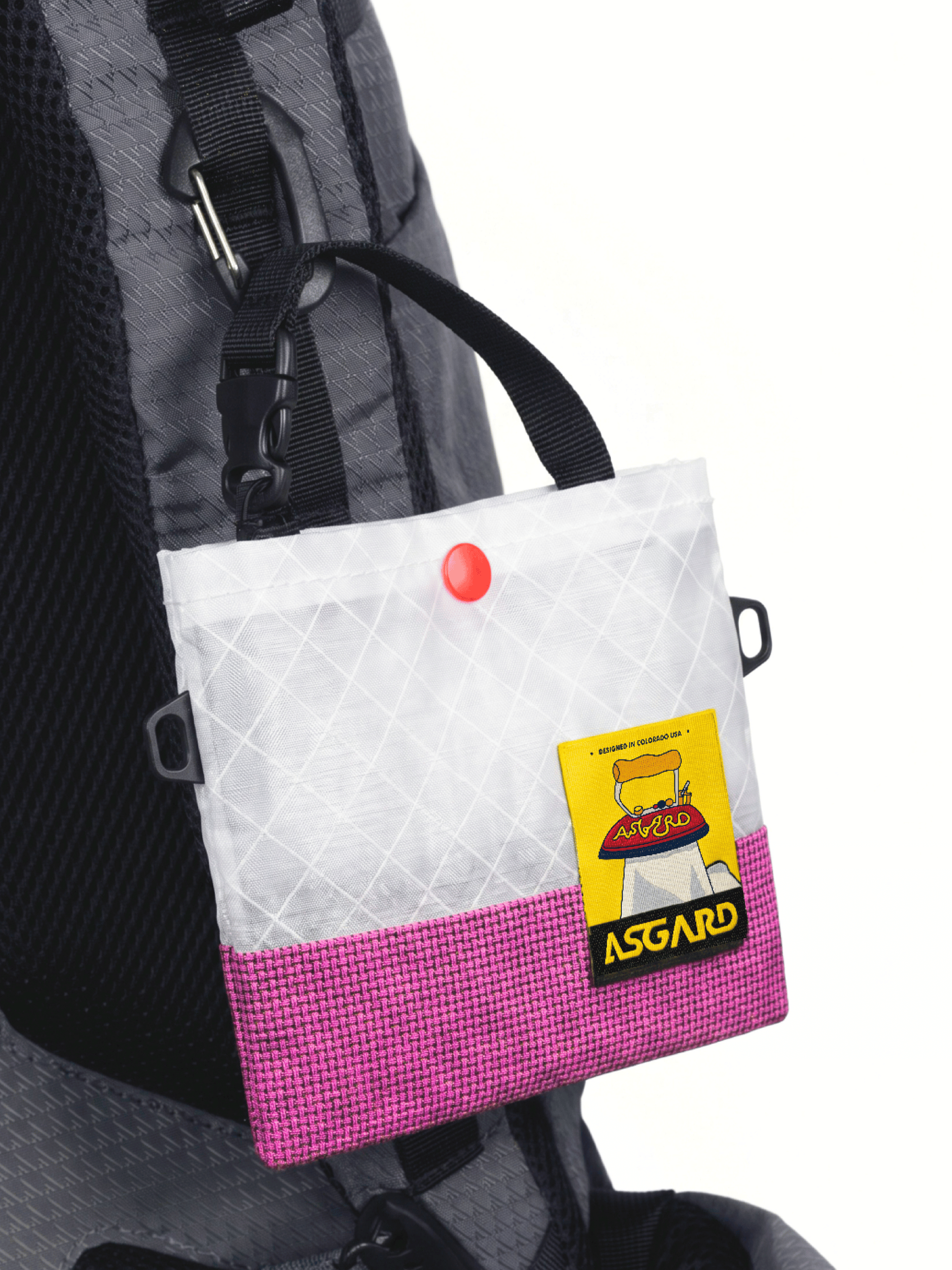 Pink Asgard Mini Tote Bag hanging from a black clip on a gray backpack shoulder strap.